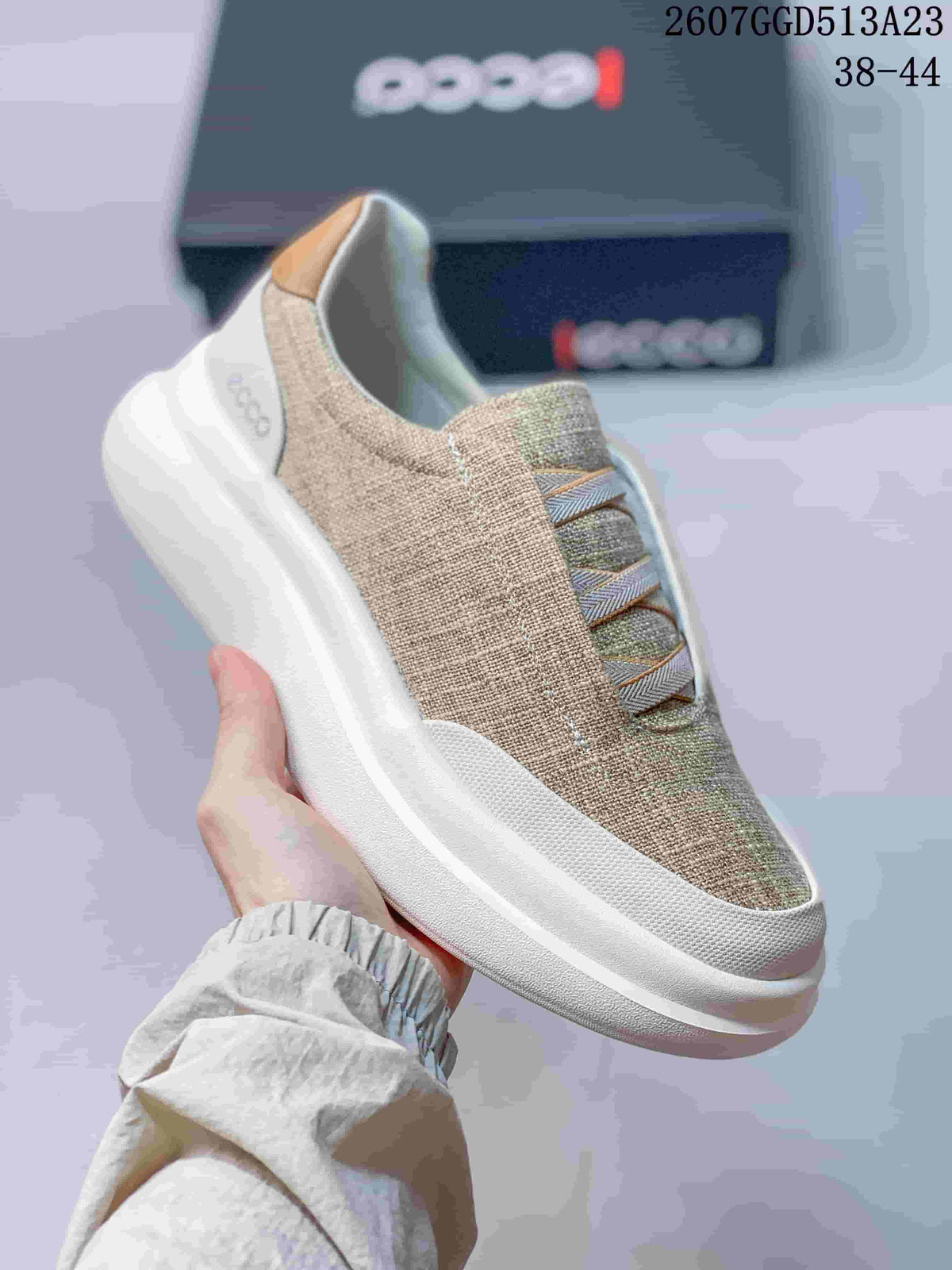 Side view of a beige ECCO slip-on sneaker showing the elastic cross straps, padded collar and thick white outsole.