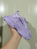 Purple Balenciaga Triple S sneaker shown from the side in a hand-held close-up.