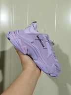 Purple Balenciaga Triple S sneaker shown from the side in a hand-held close-up.