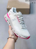 Angled side view showing the white sneaker, gray On branding, pink outsole accents, and visible midsole cutouts.