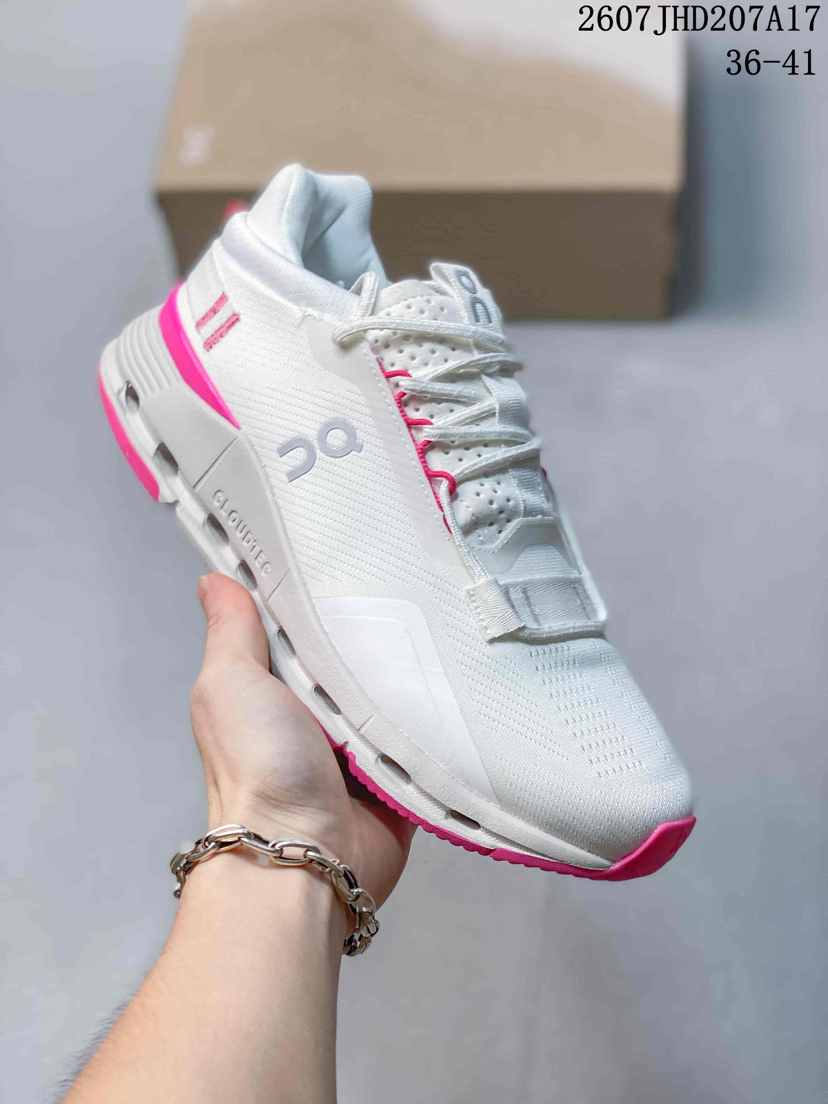 Angled side view showing the white sneaker, gray On branding, pink outsole accents, and visible midsole cutouts.