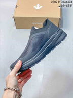 Side profile of the dark gray low-top slip-on sneaker showing its layered upper and sole design.