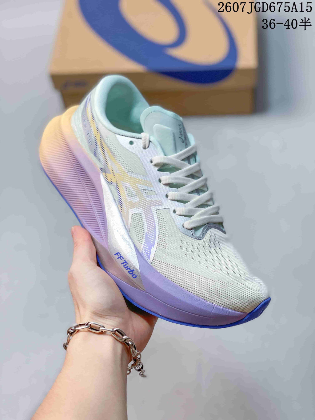 Light-colored ASICS Magic Speed 4 running shoe with pale blue and lavender accents, shown beside a shoe box.