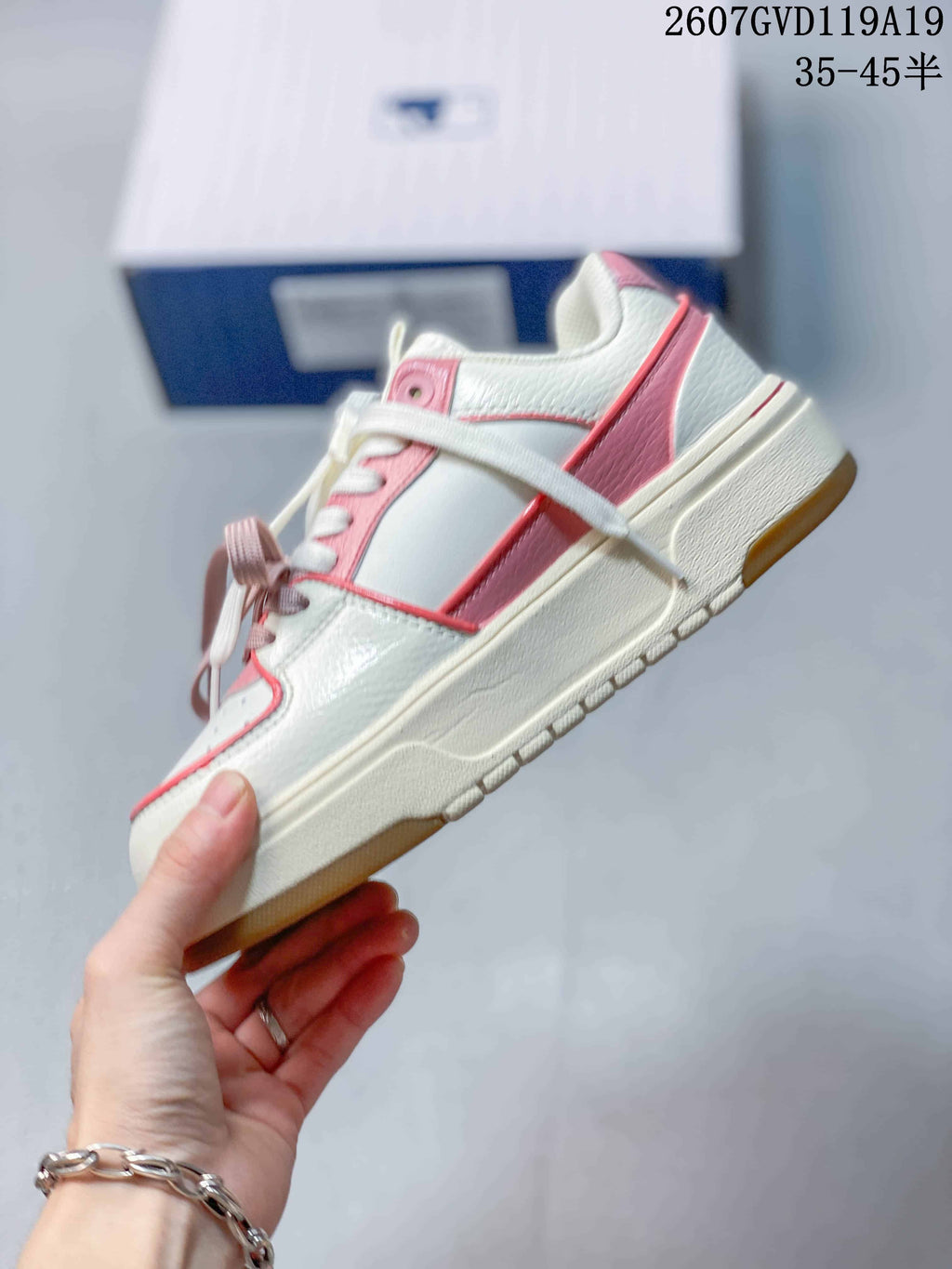Side view of the low-top sneaker showing white and pink panels, layered trim, a raised midsole and gum-colored outsole.
