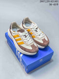 Pair of off-white, taupe, and yellow Adidas retro sneakers on a blue box