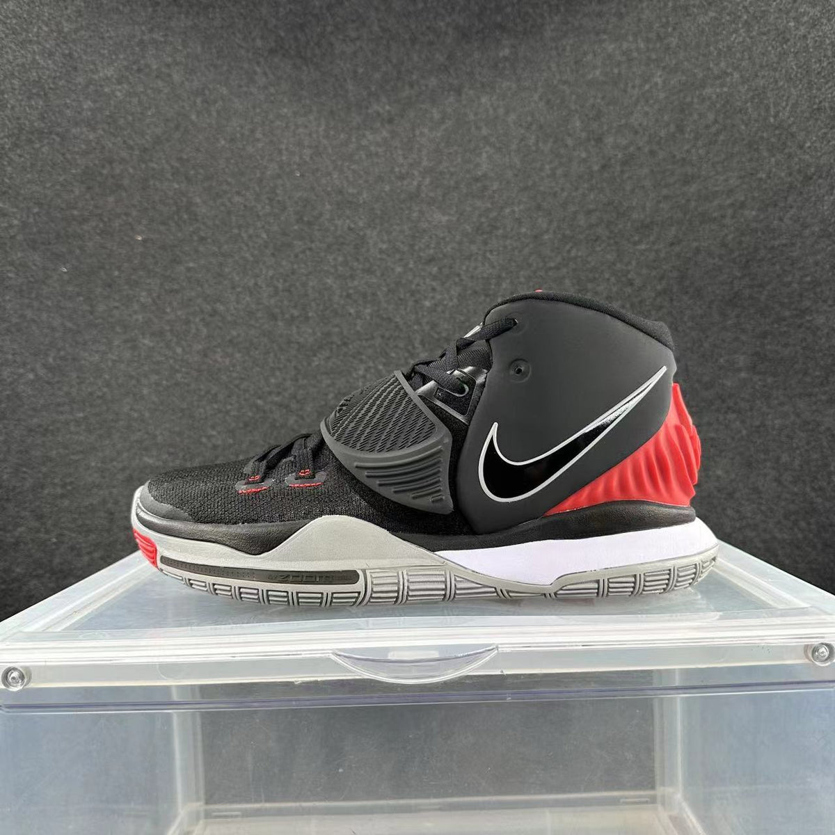 Side view of a black and red Nike high-top basketball shoe with a midfoot strap and white-edged Swoosh.