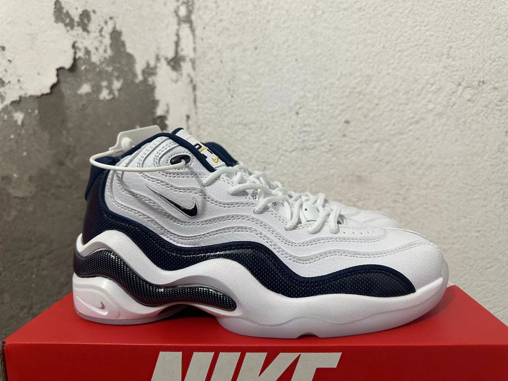 Side view of a white and navy Nike sneaker with layered panels.