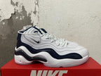 Side view of a white and navy Nike sneaker with layered panels.