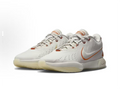 White low-top Nike basketball shoes with orange accents, shown as a pair.