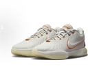 White low-top Nike basketball shoes with orange accents, shown as a pair.