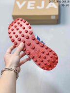 Close-up of the red textured outsole with raised geometric tread elements and VEJA branding.