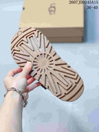 Underside of the tan sandal showing the textured lug outsole and central UGG branding.