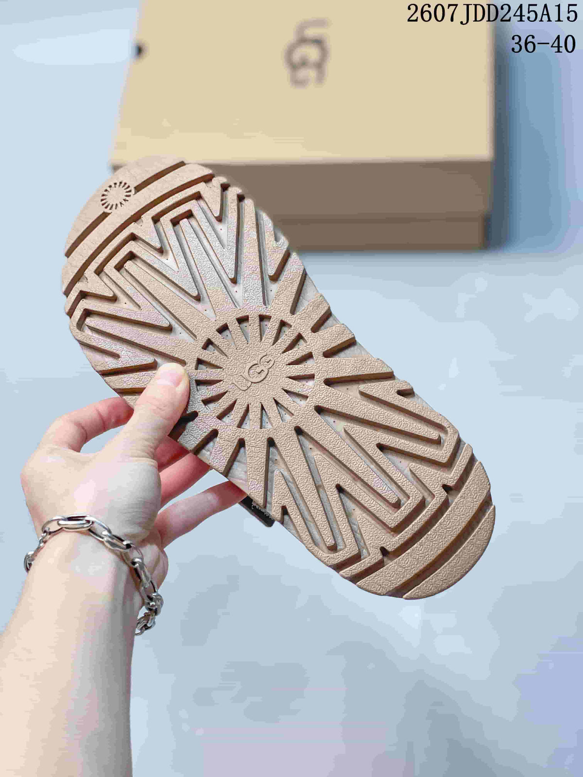Underside of the tan sandal showing the textured lug outsole and central UGG branding.