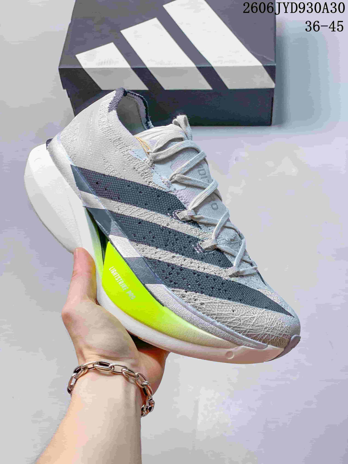 Light gray adidas Adizero Prime X3 shoe with dark stripes and a neon yellow sole accent.