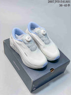 White Descente running shoes with light blue accents and dial closures, displayed on a box.