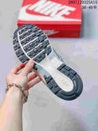 Underside view of the sneaker showing the segmented black-and-white outsole and red Nike shoebox in the background.