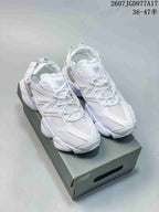 Pair of predominantly white New Balance 9060 sneakers displayed on a shoebox, showing the chunky sole and adjustable heel straps.