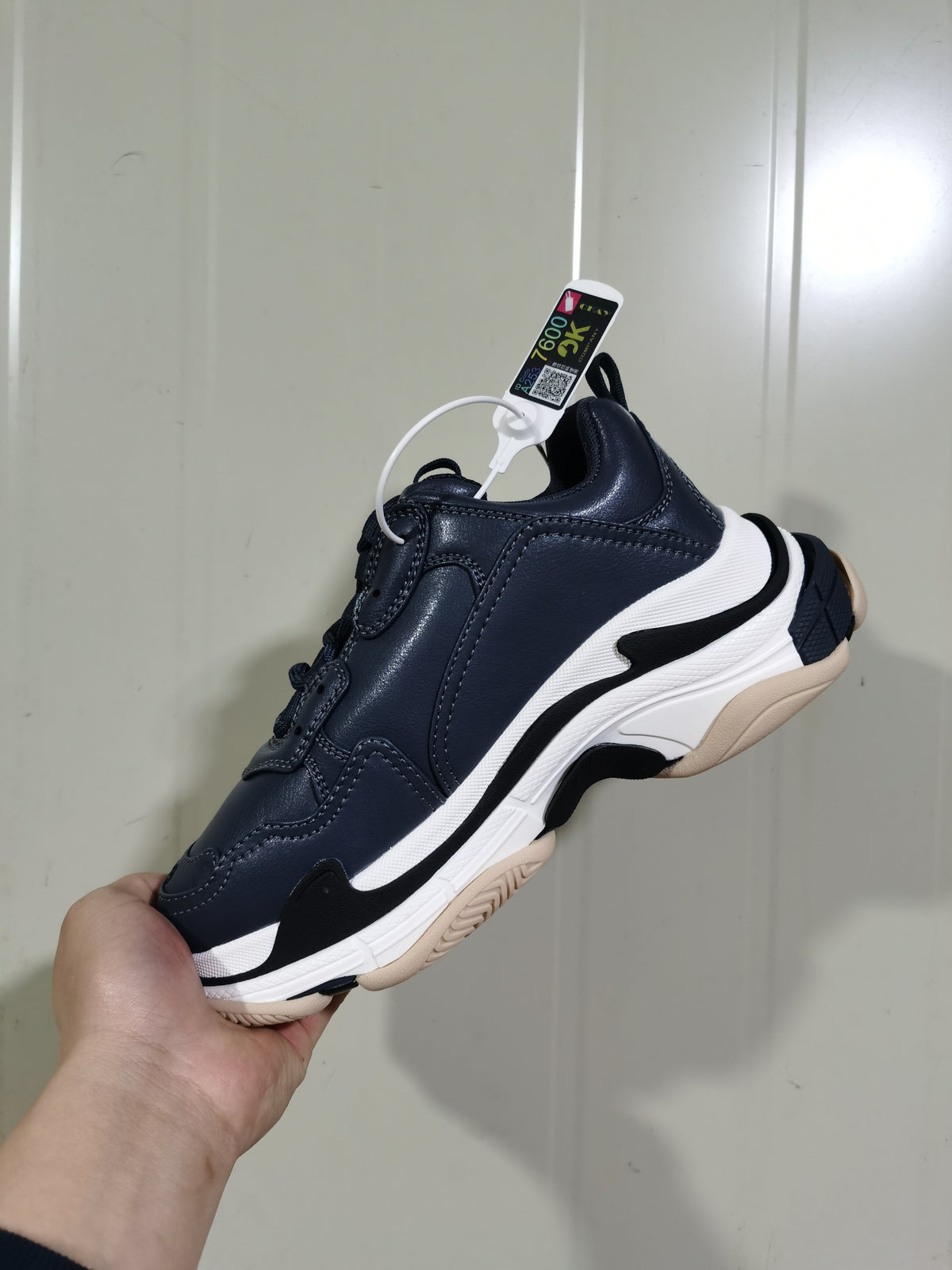Side view of a dark blue-grey Balenciaga Triple S sneaker showing layered white and black sole details and a textured outsole.