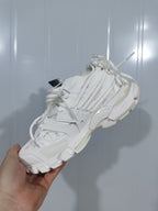 Top and side view of the white sneaker highlighting its layered panels, multiple laces, and sculpted outsole.