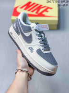 Close-up of a white and navy-gray low-top sneaker showing the side overlay, perforated toe box, AIR midsole marking, and dark outsole.