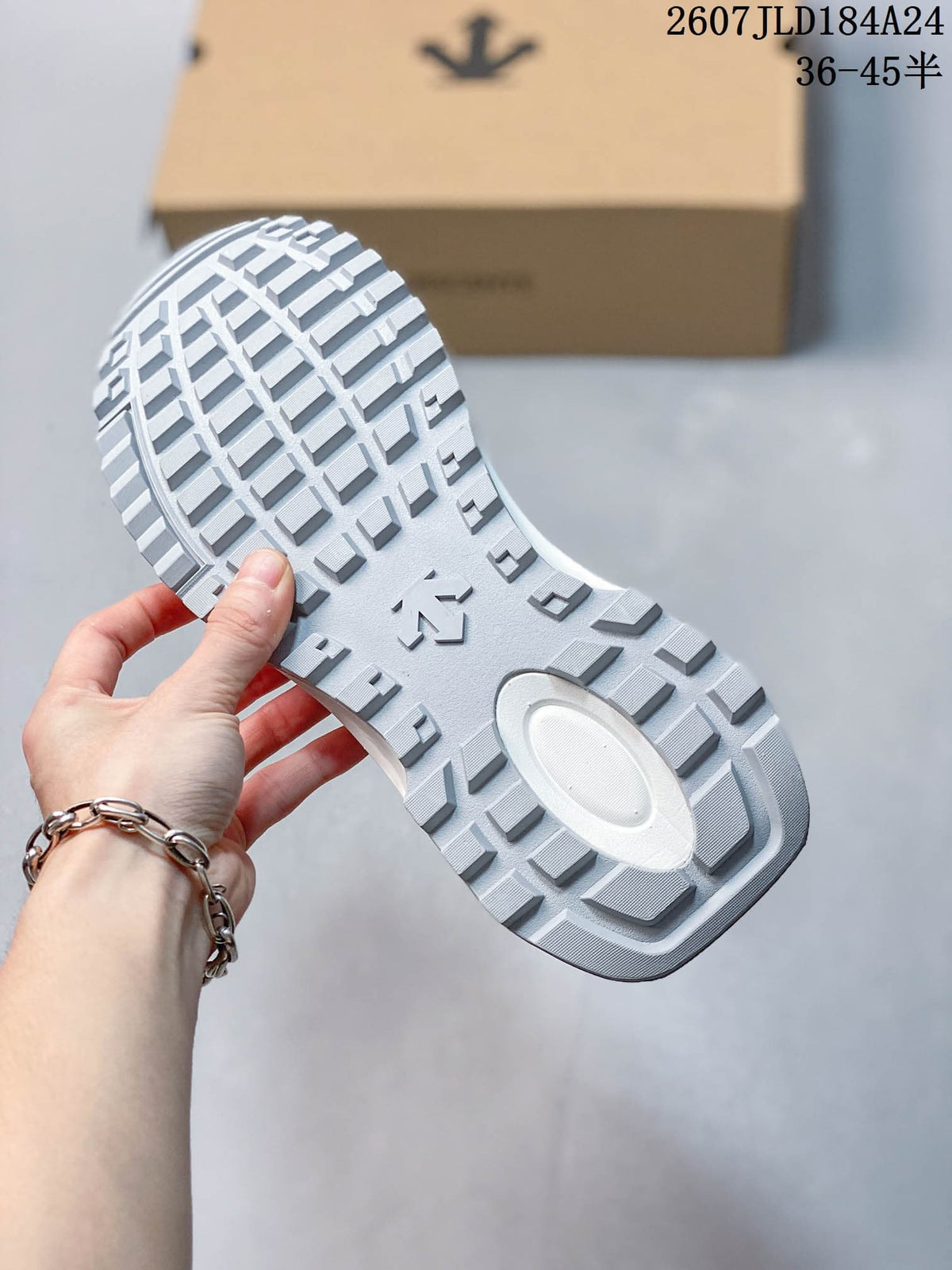 Close view of the white sneaker outsole showing a geometric block tread pattern and central logo detail.