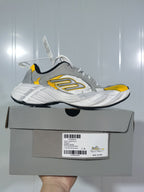 Side view of the gray, white, and yellow sneaker resting on its product box; the label shows size C 39.