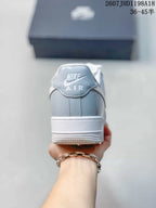 Rear view of a gray and white low-top sneaker showing the Nike Air heel branding.