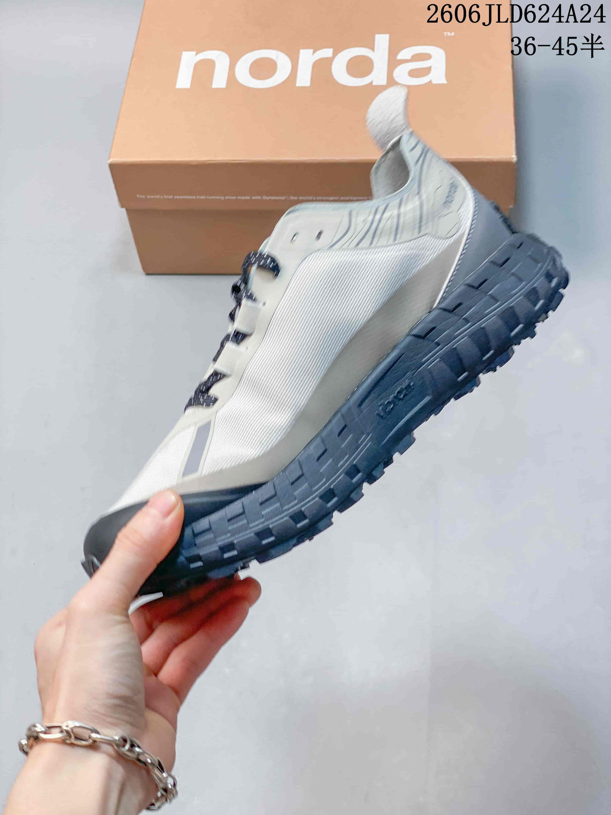Side profile of the light gray Norda hiking shoe with a dark lugged sole.