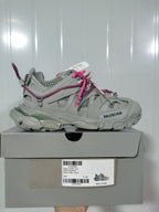 Side view of a grey Balenciaga Track sneaker with pink rope laces resting on its labeled shoe box.
