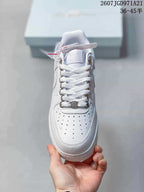 Front view of the white sneaker showing the perforated toe box, white laces, and metallic eyelets.