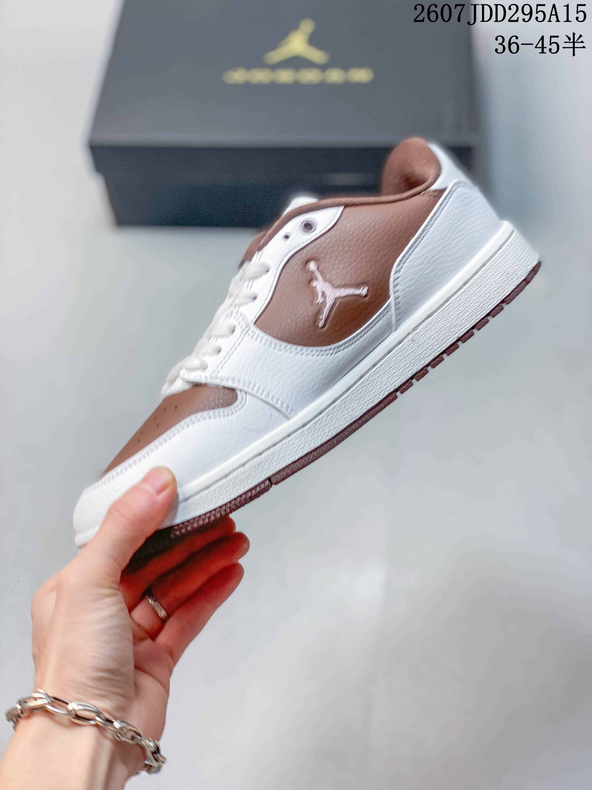 Side view of a white and brown low-top sneaker showing the Jordan side logo, layered panels, white midsole, and brown outsole.