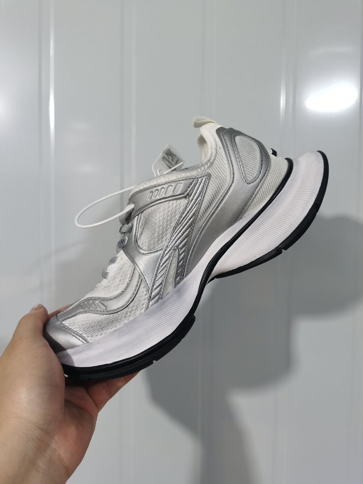 Side view of a white and silver Balenciaga Circuit sneaker showing layered panels, mesh sections, sculpted midsole, and black outsole.