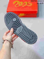 Close-up of the dark textured rubber outsole with circular and grid traction patterns; a red presentation box is in the background.