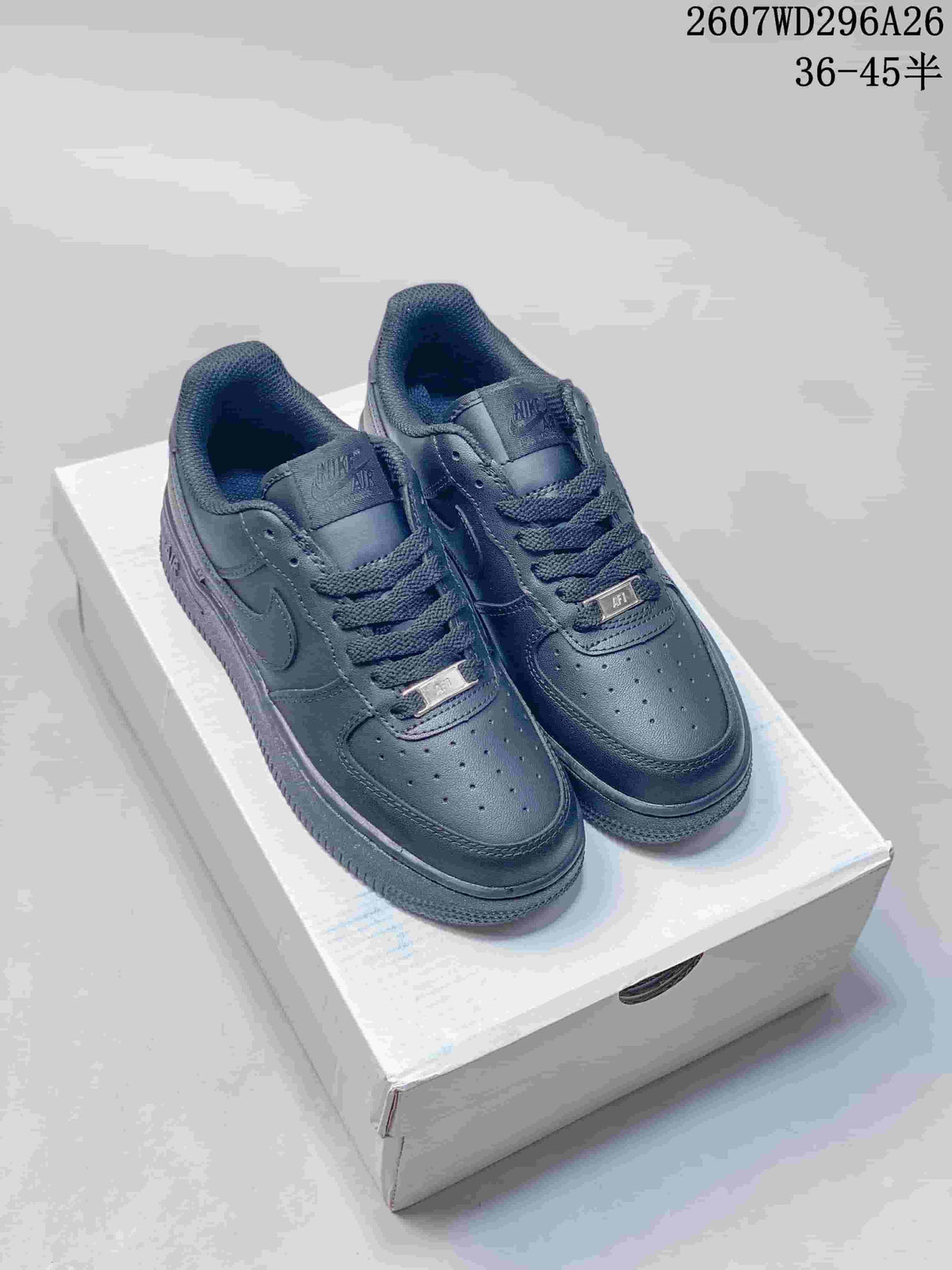 Pair of black low-top sneakers displayed on a shoebox, with perforated toe panels, swoosh detailing and lace-up closures.