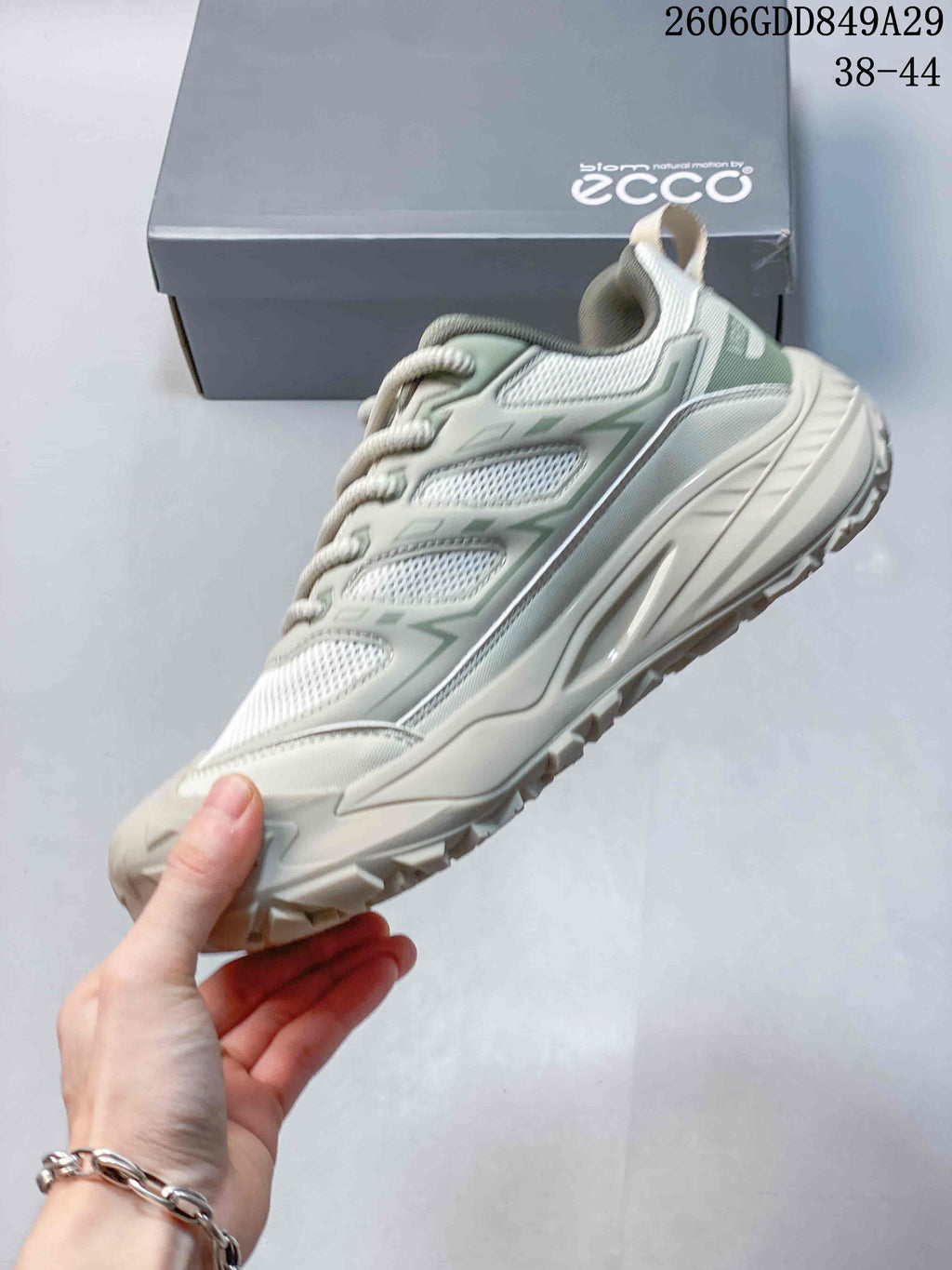 Side profile of a light gray mesh sneaker with muted green details