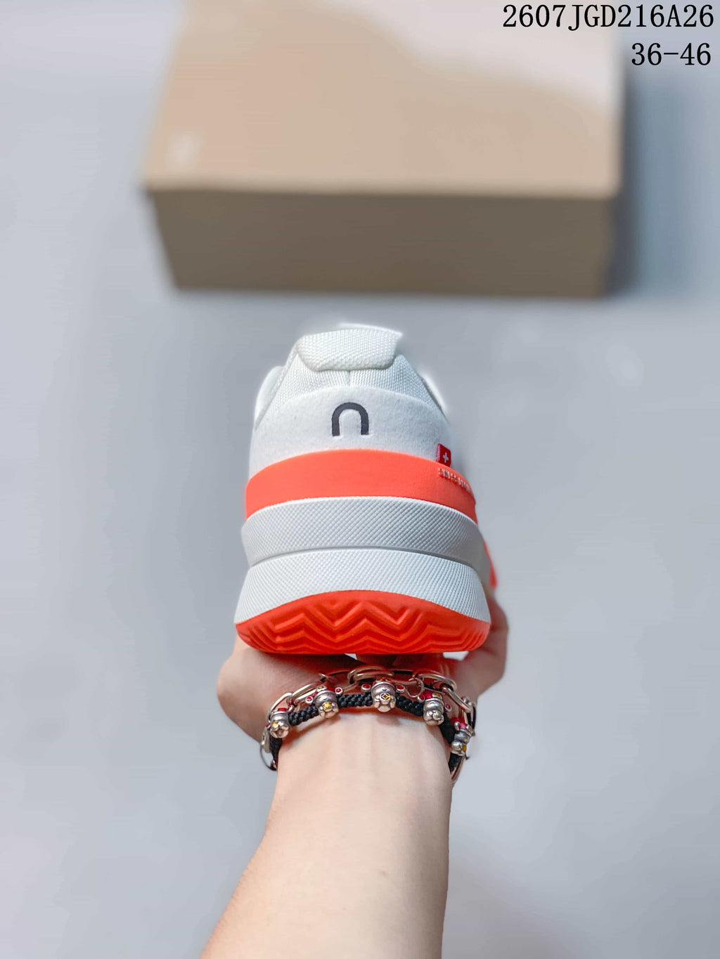 Rear view of the sneaker showing the padded heel, white midsole and bright orange heel and outsole details.