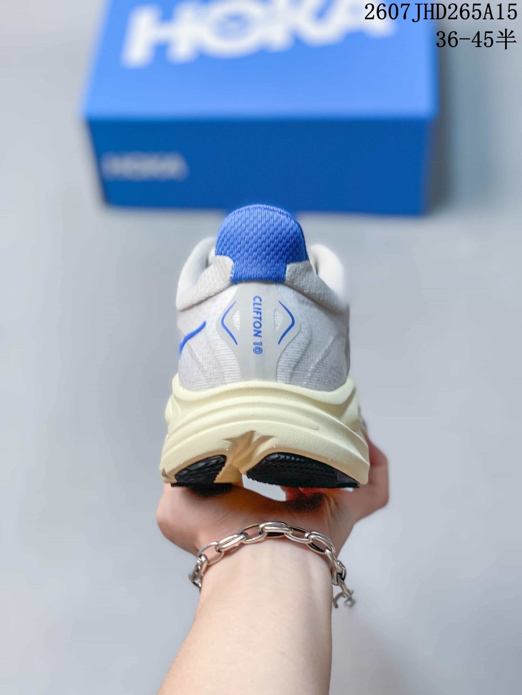 Rear view of a HOKA Clifton 10 sneaker showing the blue heel tab, padded collar, and sculpted sole.