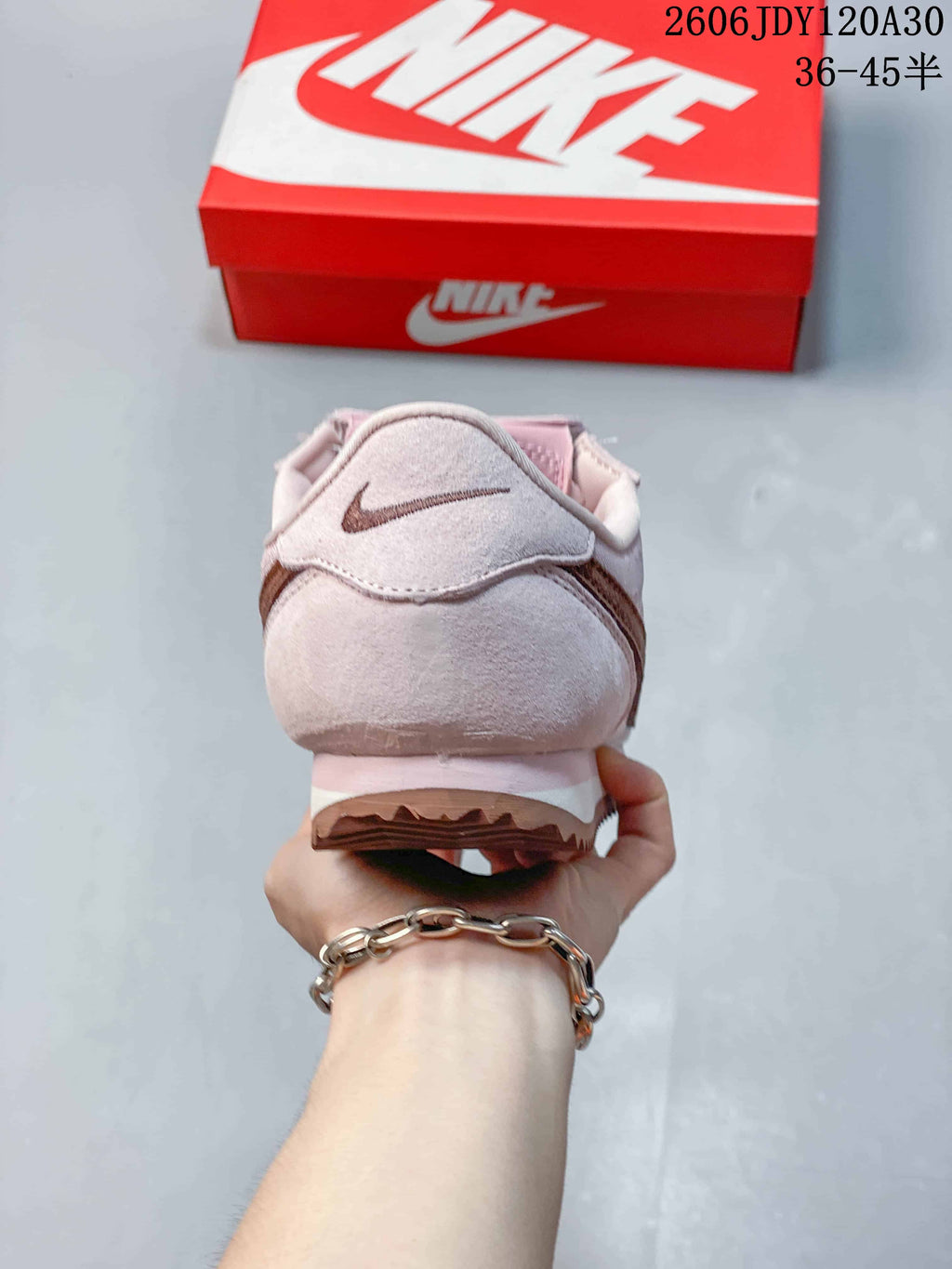 Rear view of a pale pink Nike Classic Cortez sneaker with a brown heel accent