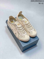 Pair of cream-toned Onitsuka Tiger MEXICO 66 sneakers displayed on a shoebox, showing the textile upper, laces, and low-top profile.