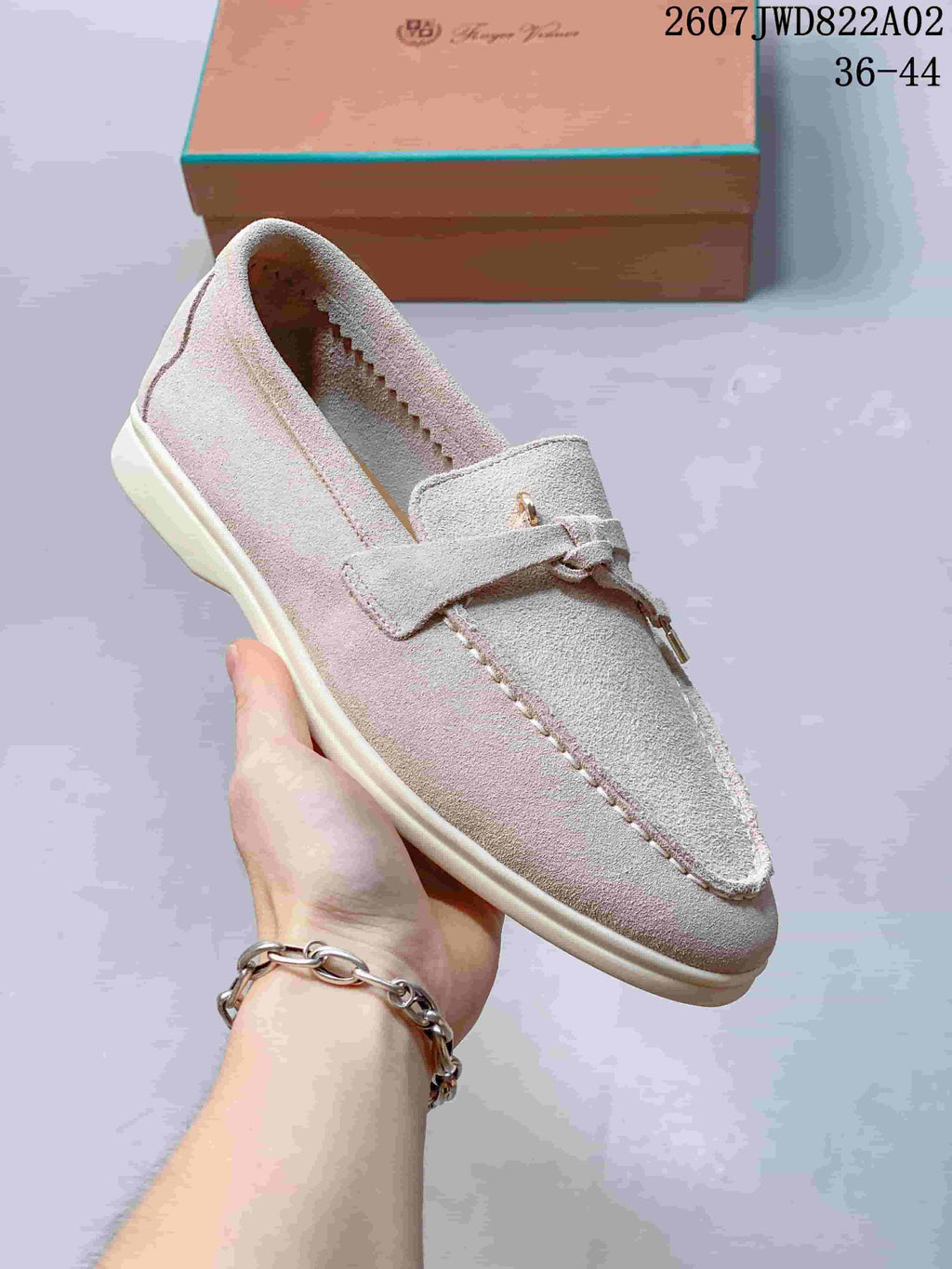 Close view of a pale neutral loafer with strap and tassel accents