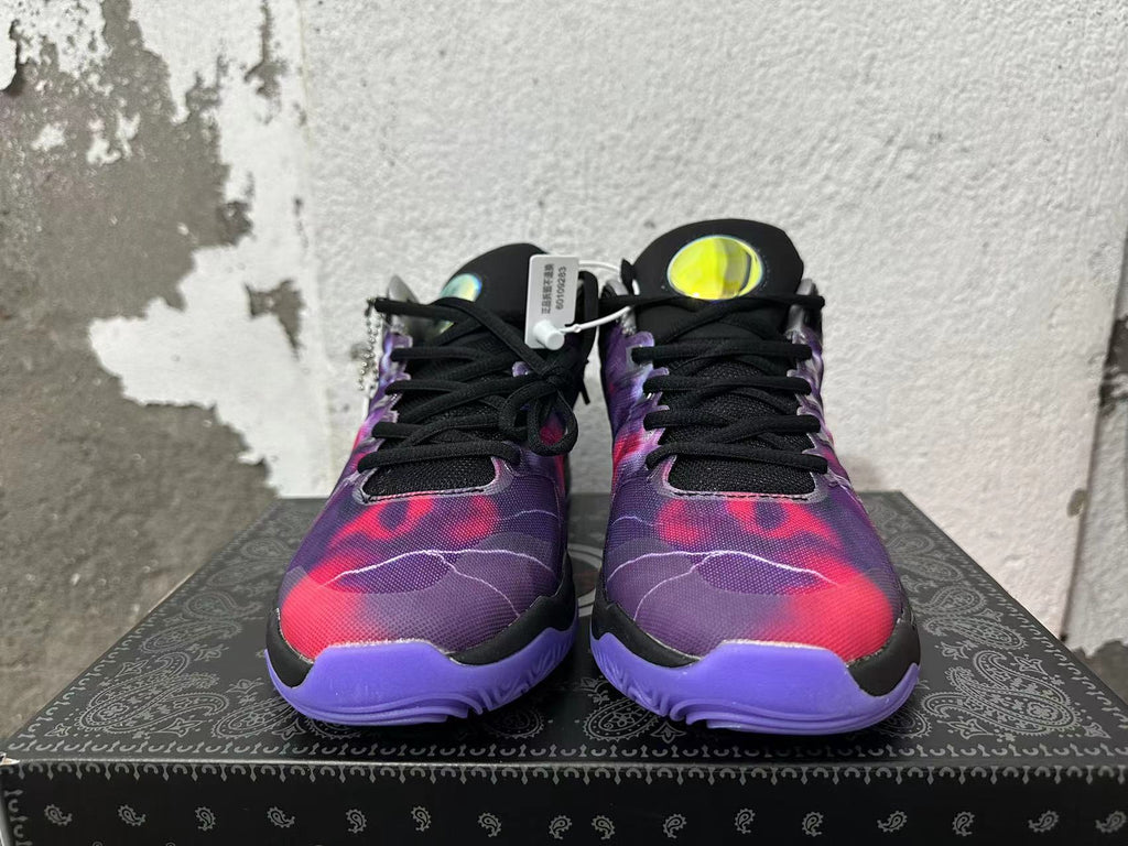 Front view of black and purple Nike basketball-style sneakers with red patterned uppers and black laces