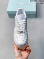 Top view of the white sneaker showing the perforated toe box, laces and metallic lace tag.