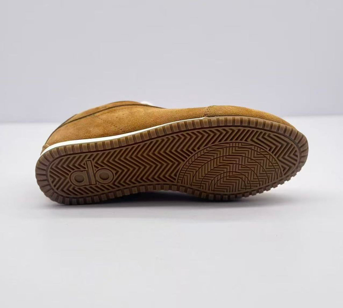 Underside view showing the brown rubber outsole with chevron and geometric tread patterns.