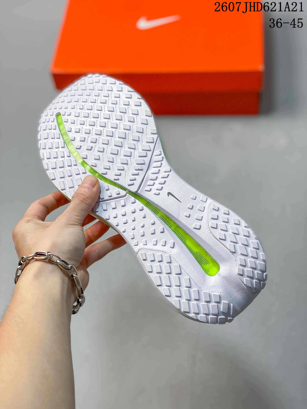 Underside view showing the white textured outsoles and bright green central cushioning sections.
