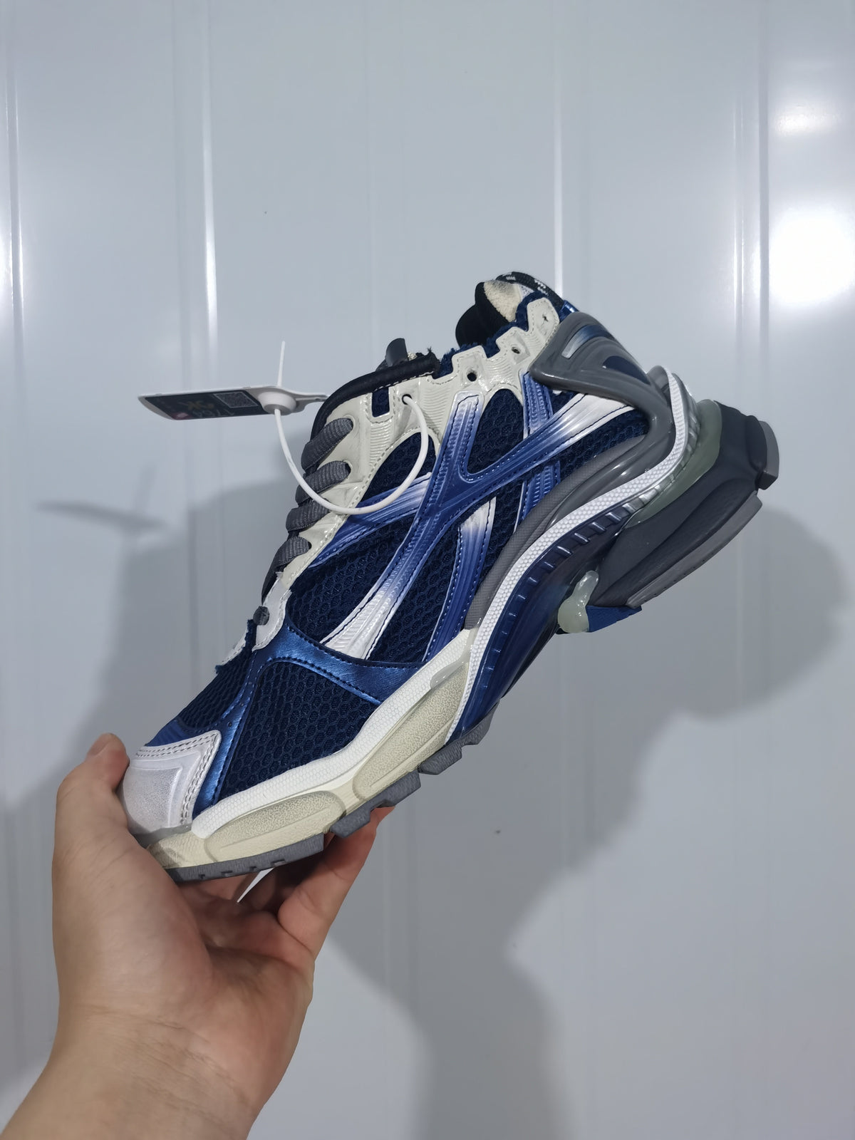 Side view of the beige, navy and grey Balenciaga Runner sneaker showing mesh panels, layered overlays and the outsole.