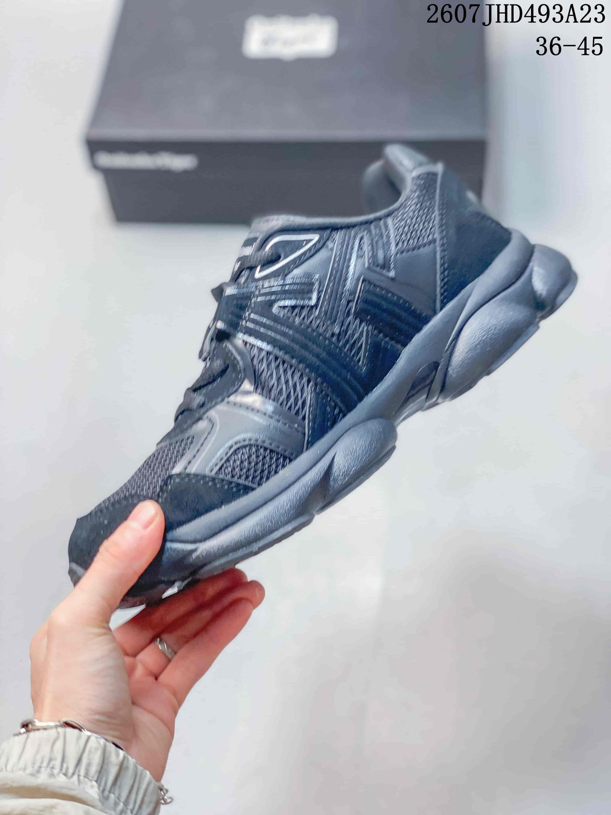 Side profile of the dark Onitsuka Tiger sneaker showing layered panels, mesh sections and the chunky sole.