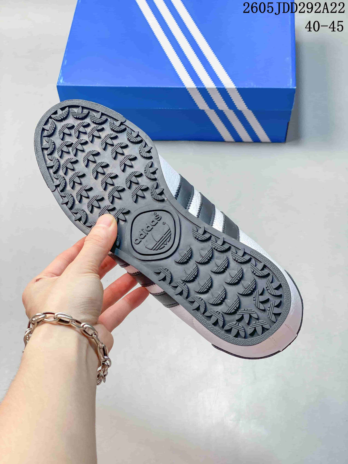Bottom view of a sneaker showing the textured outsole with repeated trefoil-shaped tread details.