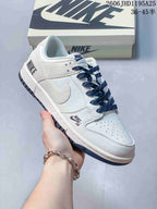 Close view of a white low-top sneaker with navy laces, perforated toe box, and dark outsole accents.