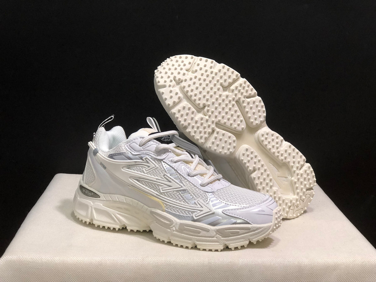 Three-quarter view of the white sneakers with one shoe lifted to display the raised outsole tread.