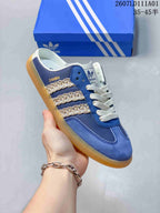 Close view of a blue mule sneaker with decorative side stripes, white laces, and gum-colored outsole.